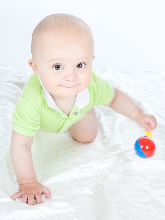 Bebé con un traqueteo. Siete meses lindos del bebé que juega con un traqueteo