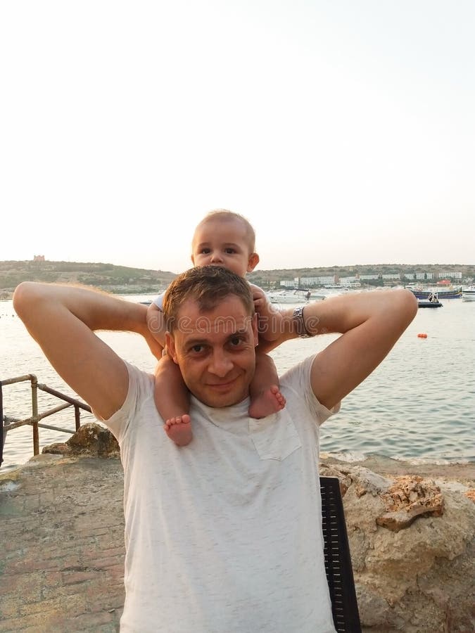 Bebé de cuatro meses que se sienta en cuello del papá s imagenes de archivo Bebé de cuatro meses que se sienta en cuello del papá s imagenes de archivo