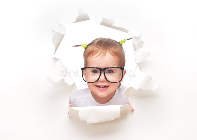 Bebé del niño con las colas divertidas con los vidrios que mira furtivamente a través de un agujero en el Libro Blanco fotos de archivo Bebé del niño con las colas divertidas con los vidrios que mira furtivamente a través de un agujero en el Libro Blanco fotos de archivo