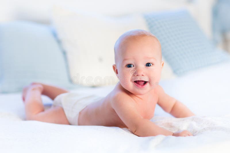 Baby boy wearing diaper in white sunny bedroom. Newborn child relaxing in bed. Nursery for children. Textile and bedding for kids. Family morning at home. New born kid during tummy time with toy bear. Baby boy wearing diaper in white sunny bedroom. Newborn child relaxing in bed. Nursery for children. Textile and bedding for kids. Family morning at home. New born kid during tummy time with toy bear.