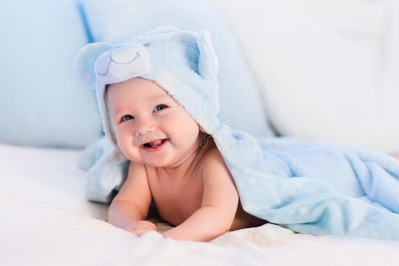 Bebé en toalla azul en la cama blanca