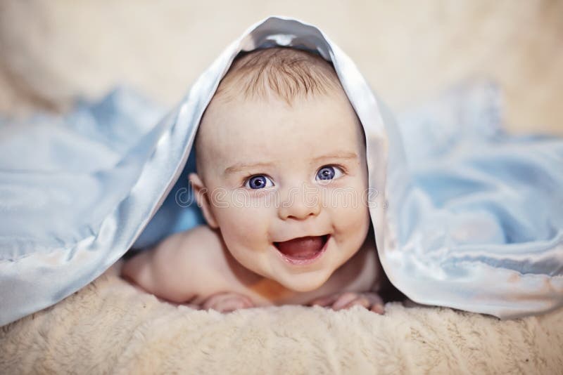 Bebé feliz debajo de la manta foto de archivo libre de regalías