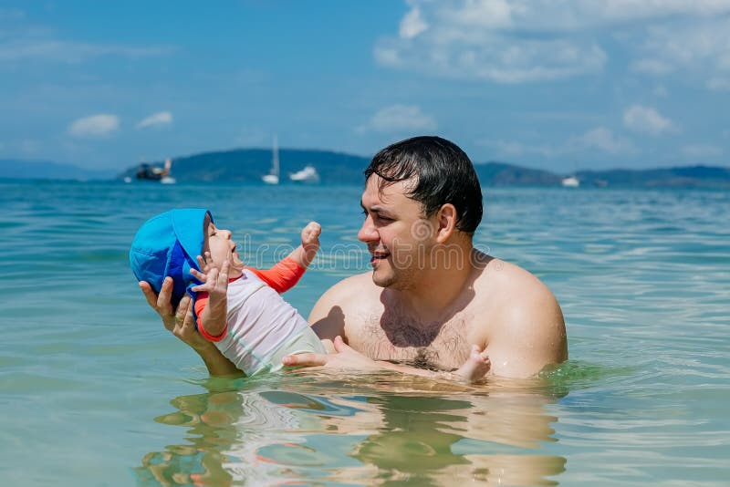 Bebé infantil de risa feliz con el papá que se divierte en el mar El padre enseña a la hija a nadar y a regar foto de archivo Bebé infantil de risa feliz con el papá que se divierte en el mar El padre enseña a la hija a nadar y a regar foto de archivo