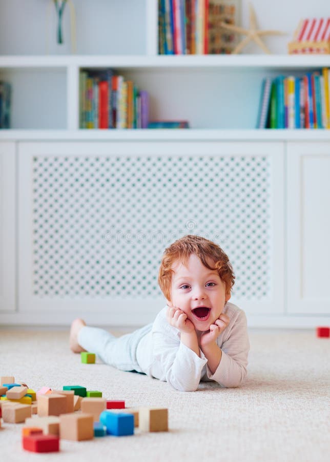 Bebé lindo del niño que juega con los bloques de madera en la alfombra fotos de archivo libres de regalías Bebé lindo del niño que juega con los bloques de madera en la alfombra fotos de archivo libres de regalías