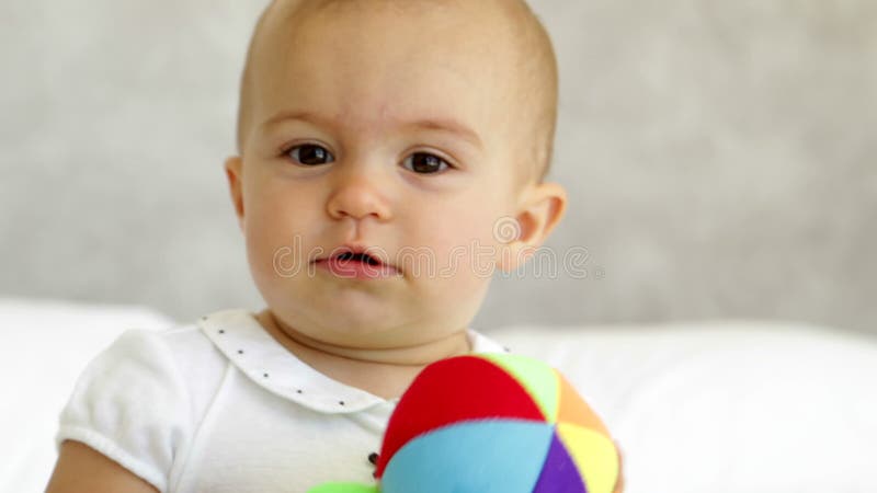 Bebé lindo que juega con la bola suave en cama almacen de video