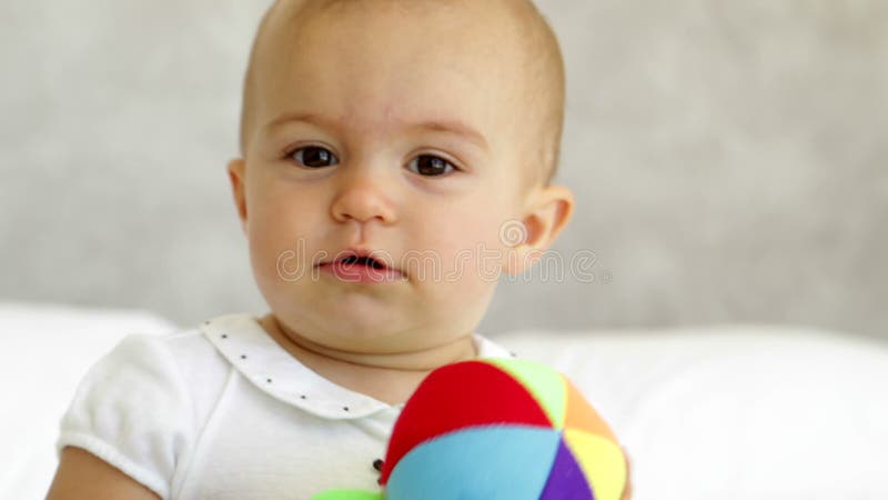 Bebé lindo que juega con la bola suave en cama