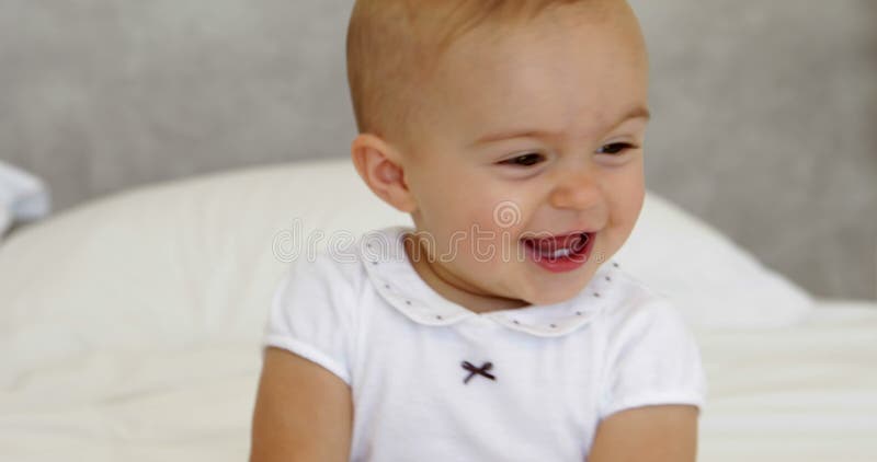 Bebé lindo que juega con la toalla en cama almacen de video