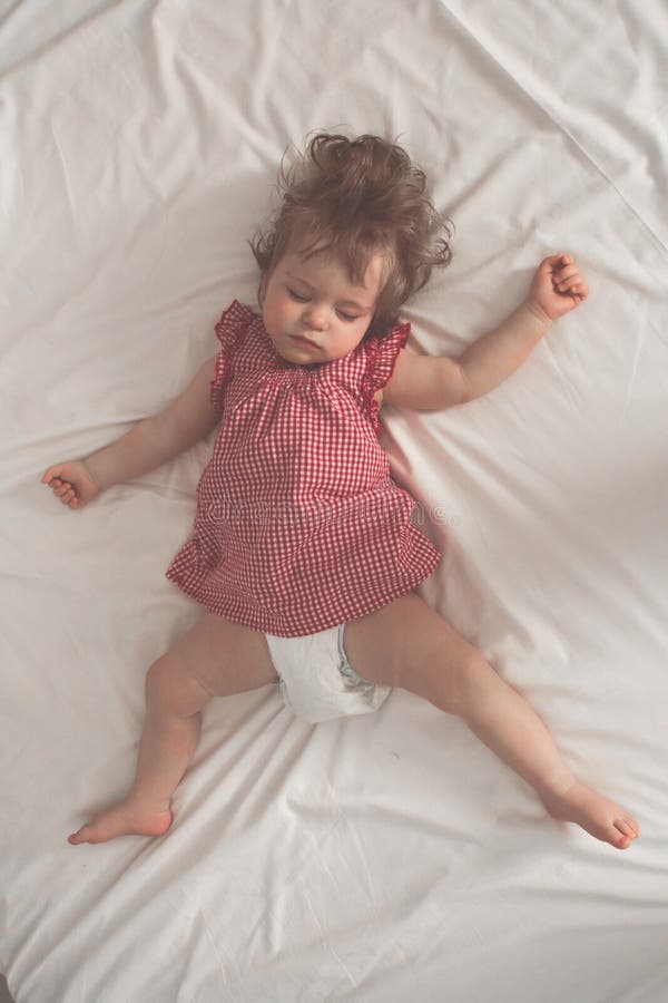 Bebé que duerme en la parte posterior con los brazos abiertos y sin el pacificador en una cama con las hojas blancas El dormir pa imagen de archivo Bebé que duerme en la parte posterior con los brazos abiertos y sin el pacificador en una cama con las hojas blancas El dormir pa imagen de archivo