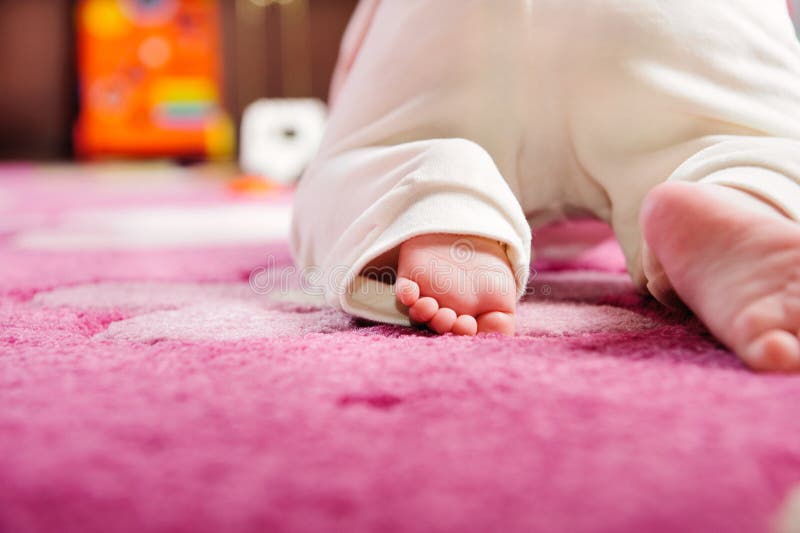 Bebé que se arrastra en la alfombra rosada
