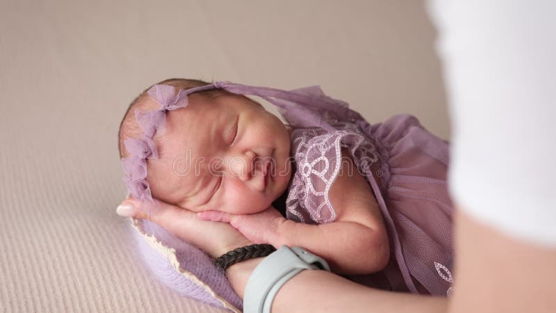 Bebé recién nacida vestido de lacayo durmiendo en manos de la madre metrajes