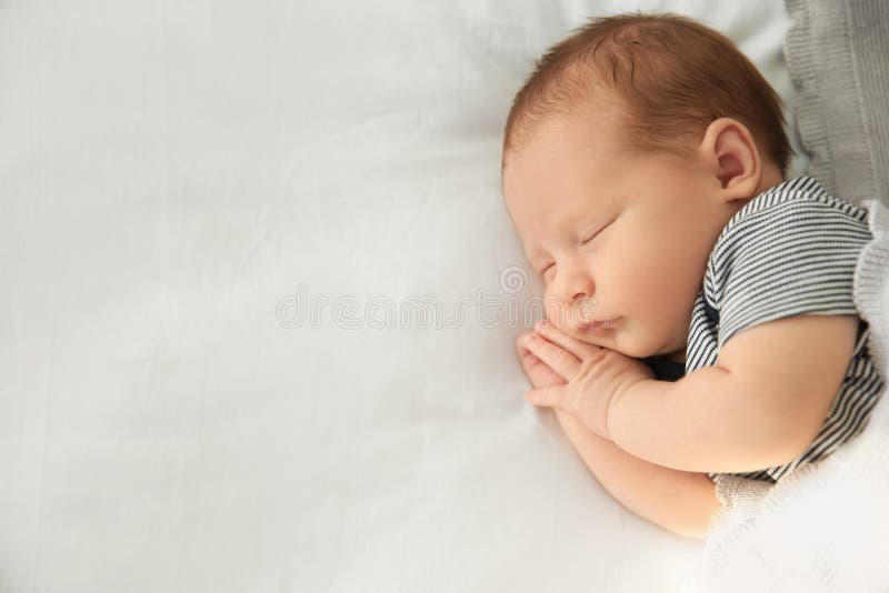 Bebé recién nacido adorable que duerme pacífico en cama