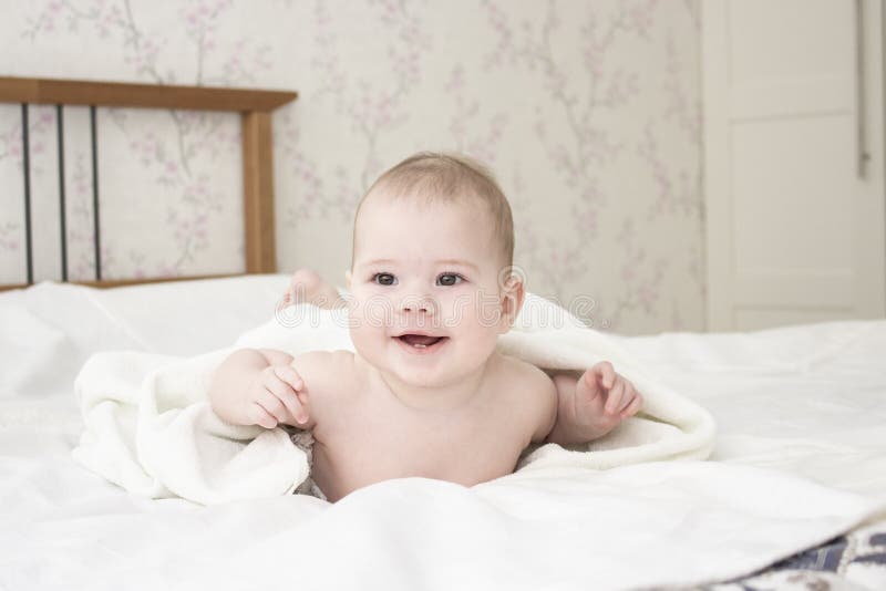 Bebé sonriente alegre en la toalla blanca después de bañar El niño ríe la mentira en su estómago De la muchacha de un año del muc imágenes de archivo libres de regalías Bebé sonriente alegre en la toalla blanca después de bañar El niño ríe la mentira en su estómago De la muchacha de un año del muc imágenes de archivo libres de regalías