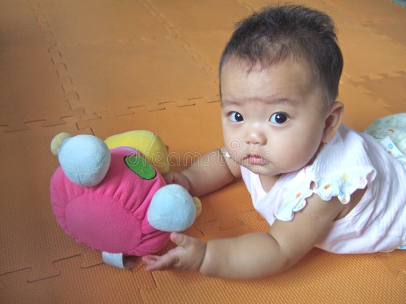 Lovely big eyes baby and toy on a yellow mat. Lovely big eyes baby and toy on a yellow mat