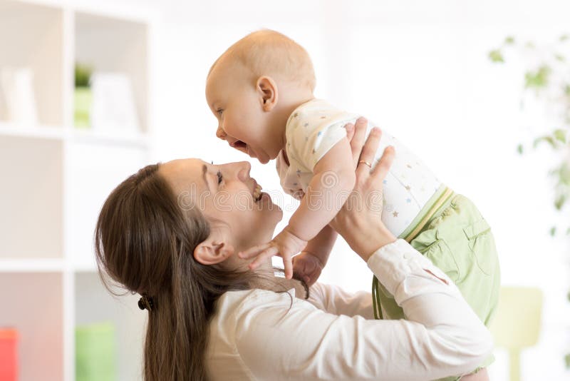 Bebé y mamá positivos Juegos jovenes de la madre con su pequeño hijo imagen de archivo libre de regalías Bebé y mamá positivos Juegos jovenes de la madre con su pequeño hijo imagen de archivo libre de regalías