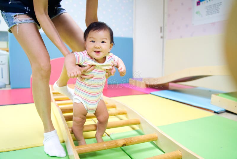 Bebê asiático de sorriso pequeno novo para apreciar jogar no campo de jogos da criança foto de stock Bebê asiático de sorriso pequeno novo para apreciar jogar no campo de jogos da criança foto de stock