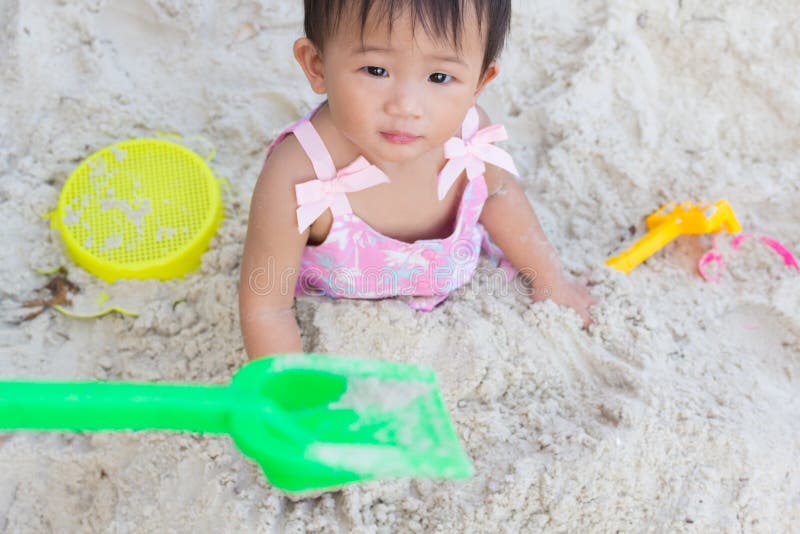 Bebê bonito asiático que joga brinquedos na praia da areia imagens de stock royalty free Bebê bonito asiático que joga brinquedos na praia da areia imagens de stock royalty free