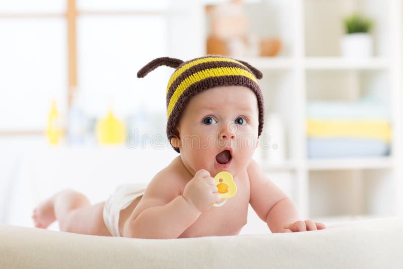 Bebê bonito com a chupeta na cama em casa fotografia de stock Bebê bonito com a chupeta na cama em casa fotografia de stock