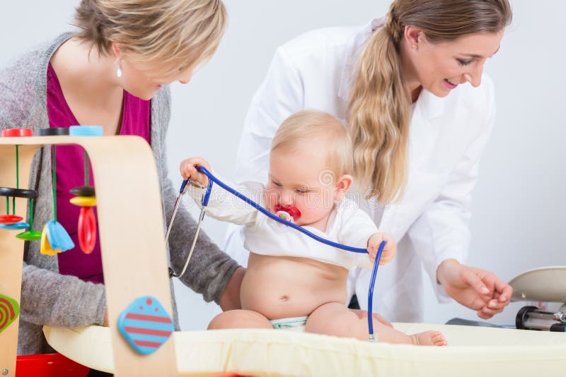 Bebê bonito e saudável que joga com o estetoscópio durante o controle rotineiro foto de stock Bebê bonito e saudável que joga com o estetoscópio durante o controle rotineiro foto de stock