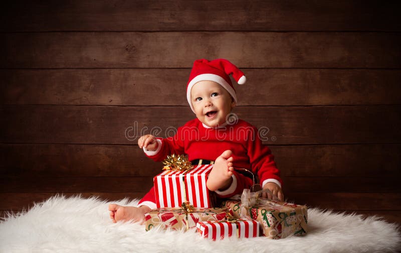Bebê bonito Santa Claus Happy Smiling que senta-se com presentes de Natal imagens de stock Bebê bonito Santa Claus Happy Smiling que senta-se com presentes de Natal imagens de stock