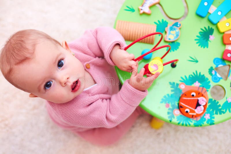 Bebê curioso que joga com desenvolver o brinquedo de madeira imagem de stock Bebê curioso que joga com desenvolver o brinquedo de madeira imagem de stock