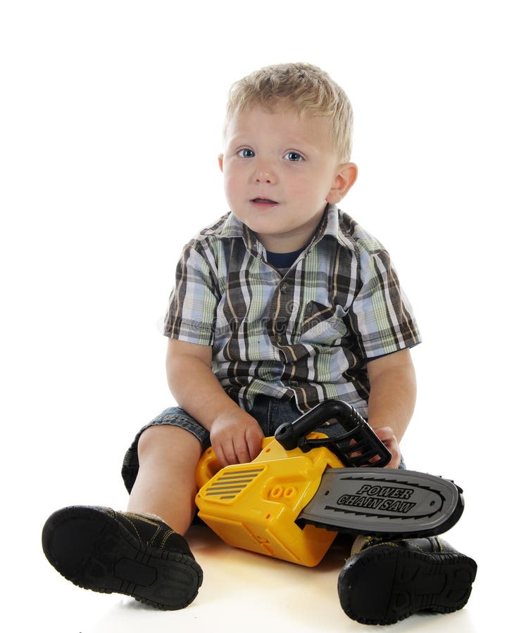 An adorable preschooler looking up as he's playing with a toy chain saw. On a white background. An adorable preschooler looking up as he's playing with a toy chain saw. On a white background.