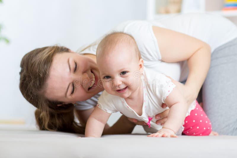 Bebê de rastejamento engraçado com mãe em casa imagens de stock Bebê de rastejamento engraçado com mãe em casa imagens de stock