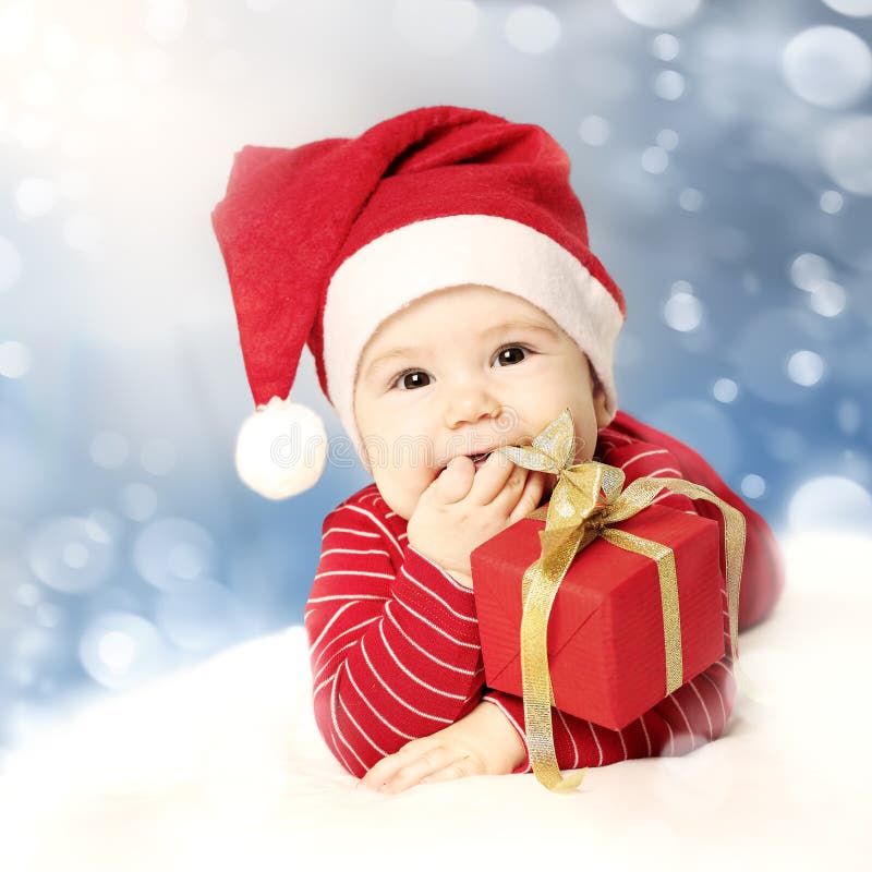 Bebê do ano novo feliz com o presente vermelho na neve imagem de stock royalty free Bebê do ano novo feliz com o presente vermelho na neve imagem de stock royalty free