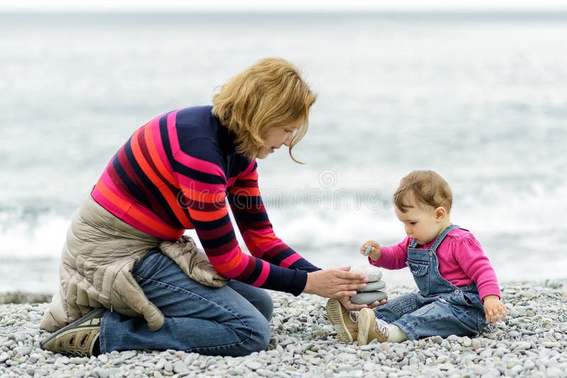 Bebê e sua mãe que jogam com seixos fotografia de stock royalty free