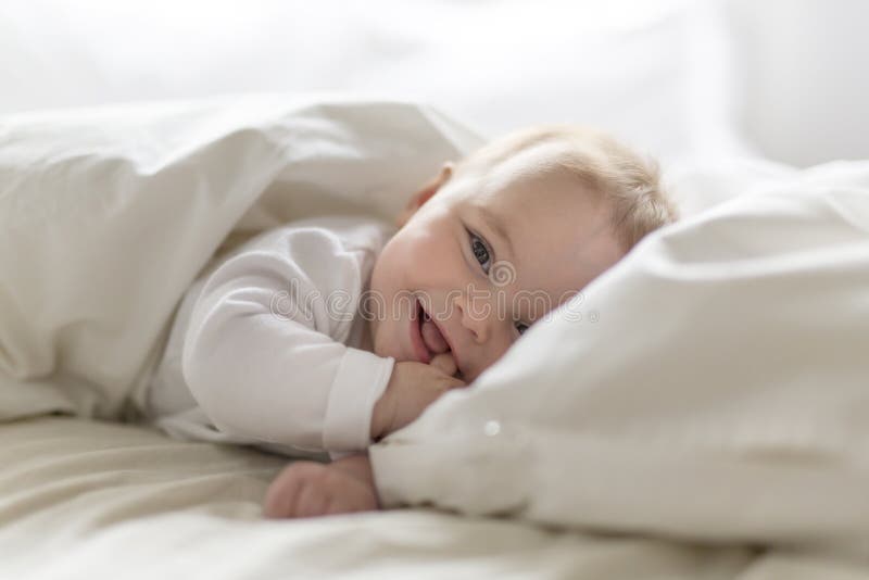 Bebê feliz bonito de 7 meses no tecido que encontra-se e que joga foto de stock Bebê feliz bonito de 7 meses no tecido que encontra-se e que joga foto de stock