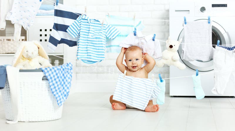 Bebê feliz do divertimento para lavar a roupa e os risos na lavanderia imagens de stock