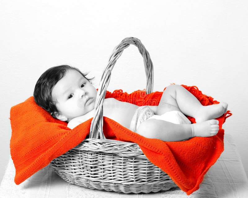 Portrait of a baby looking into the camera, laid down in a willow laundry basket on a woolen rug. Portrait of a baby looking into the camera, laid down in a willow laundry basket on a woolen rug.