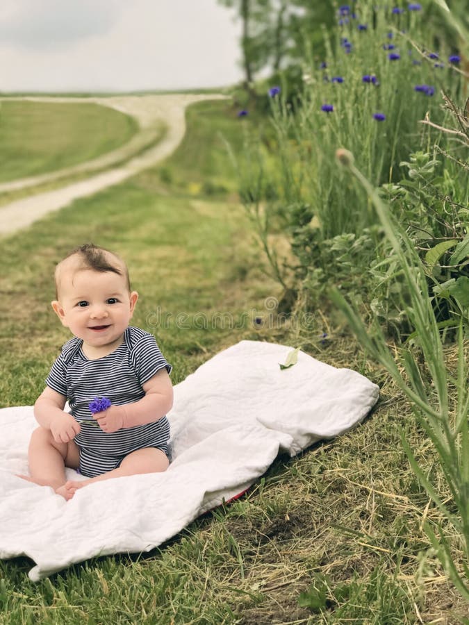 Bebê precioso do menino que senta-se na cobertura no país imagem de stock Bebê precioso do menino que senta-se na cobertura no país imagem de stock