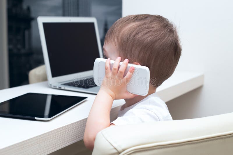Bebê que fala em um telefone celular em casa imagens de stock Bebê que fala em um telefone celular em casa imagens de stock
