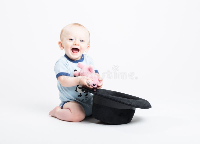 Bebê que mantém o bicho de pelúcia retirado do chapéu negro imagens de stock royalty free Bebê que mantém o bicho de pelúcia retirado do chapéu negro imagens de stock royalty free