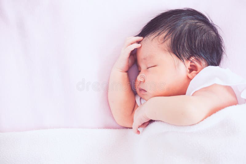 Bebê recém-nascido asiático bonito que dorme na cama imagens de stock royalty free Bebê recém-nascido asiático bonito que dorme na cama imagens de stock royalty free
