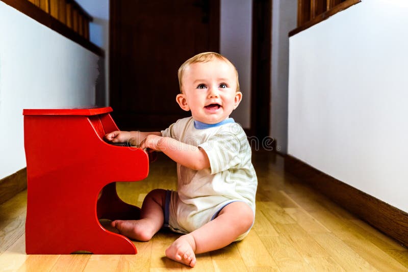 Bebê sorridente tocando piano de brinquedo enquanto aprende música foto de stock Bebê sorridente tocando piano de brinquedo enquanto aprende música foto de stock