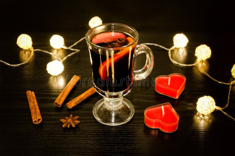 Becher Glühwein mit Gewürzen, Kerzen in Form eines Herzens, Zimtstangen, Sternanis Beleuchtung von Rattanlaternen auf a stockfoto Becher Glühwein mit Gewürzen, Kerzen in Form eines Herzens, Zimtstangen, Sternanis Beleuchtung von Rattanlaternen auf a stockfoto