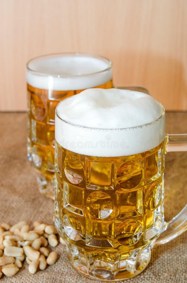 Becher mit Bier und gesalzenen Erdnüssen auf dem Tisch stockfotos Becher mit Bier und gesalzenen Erdnüssen auf dem Tisch stockfotos