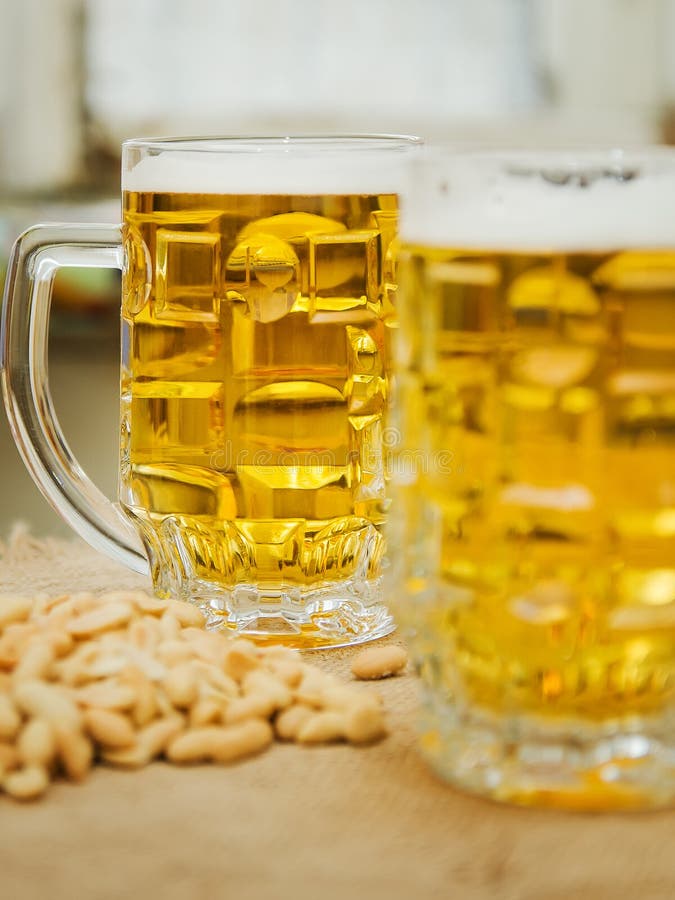 Becher mit Bier und gesalzenen Erdnüssen auf dem Tisch lizenzfreie stockfotos Becher mit Bier und gesalzenen Erdnüssen auf dem Tisch lizenzfreie stockfotos