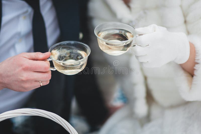 Becher mit Tee in den Händen der Braut und des Bräutigams im Winter lizenzfreies stockfoto Becher mit Tee in den Händen der Braut und des Bräutigams im Winter lizenzfreies stockfoto