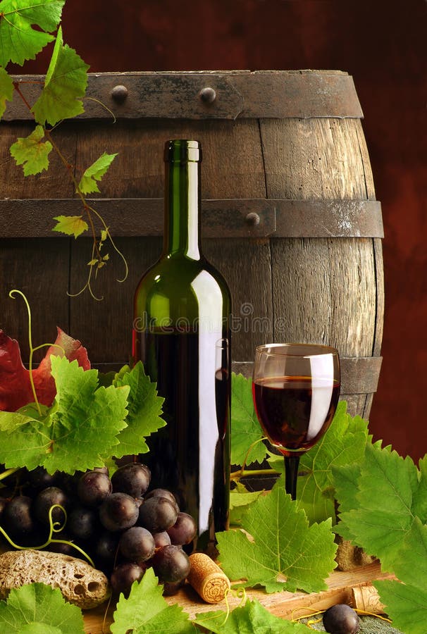 Classic red wine, bottle, glass and grapes, on dark background with barrel. Classic red wine, bottle, glass and grapes, on dark background with barrel