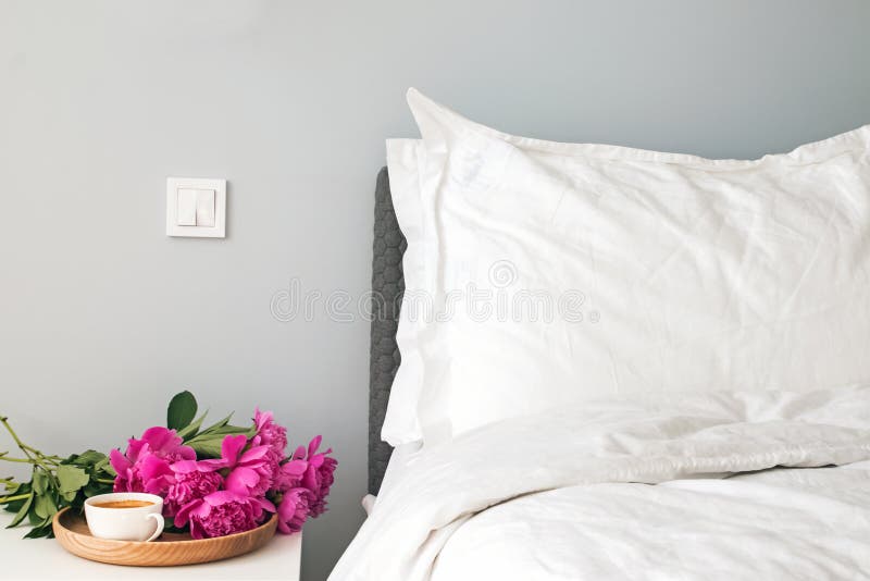 Bed met witte bedbladen en roze pioenen en koffie op nightstand royalty-vrije stock afbeelding Bed met witte bedbladen en roze pioenen en koffie op nightstand royalty-vrije stock afbeelding