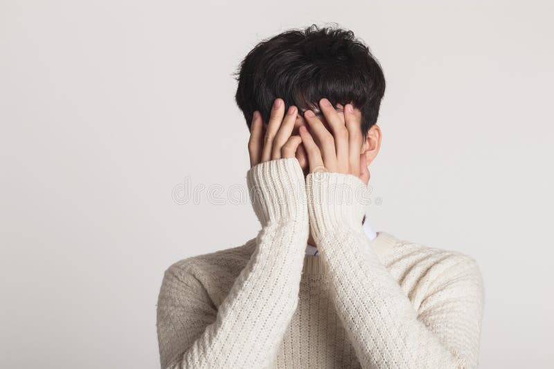 Bedecken Sie Ihr Gesicht mit Ihren Händen, Studioporträt eines traurigen asiatischen jungen Mannes lizenzfreie stockfotografie Bedecken Sie Ihr Gesicht mit Ihren Händen, Studioporträt eines traurigen asiatischen jungen Mannes lizenzfreie stockfotografie