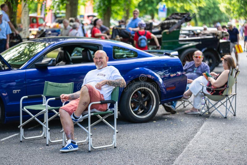 Bedford, Bedfordshire, UK Czerwiec 2, 2019 Ludzie Chłodzi za słonecznym dniu na przy festiwalem automobilizm przed Ford mustangie zdjęcia stock Bedford, Bedfordshire, UK Czerwiec 2, 2019 Ludzie Chłodzi za słonecznym dniu na przy festiwalem automobilizm przed Ford mustangie zdjęcia stock