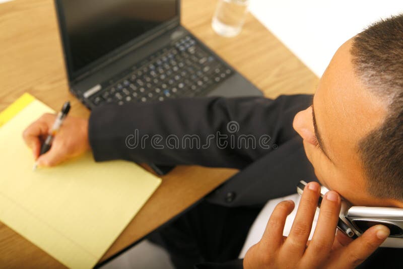 Shot of a man taking note and on the phone. focus on his head only. Shot of a man taking note and on the phone. focus on his head only