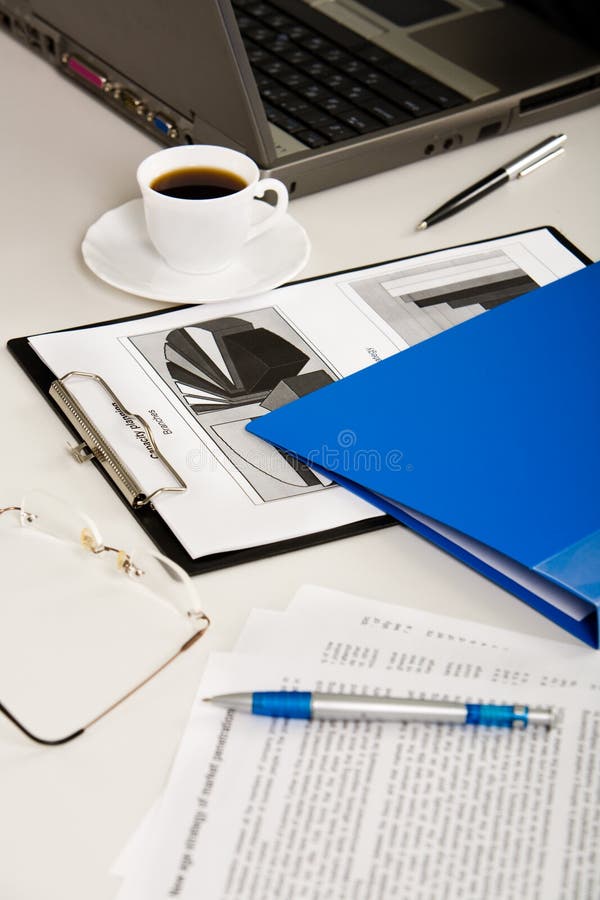 Business documents, laptop, eyeglasses, pens, folder and cup of coffee are lying on white table. Business documents, laptop, eyeglasses, pens, folder and cup of coffee are lying on white table