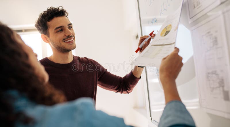 Bedrijfscollega's die het werk aangaande een whiteboard in bureau bespreken royalty-vrije stock foto's Bedrijfscollega's die het werk aangaande een whiteboard in bureau bespreken royalty-vrije stock foto's