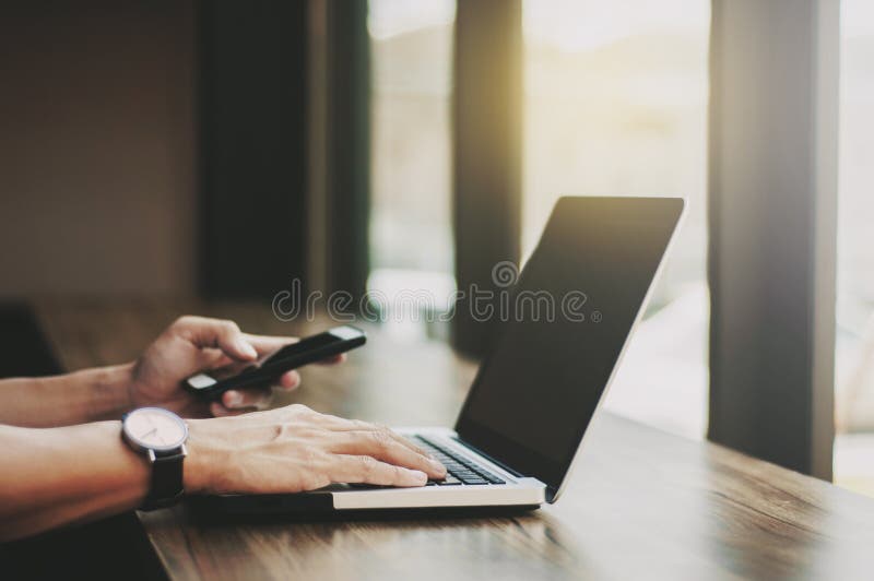 Bedrijfsmens die aan laptop werken en mobiele smartphone met behulp van op het werk royalty-vrije stock fotografie Bedrijfsmens die aan laptop werken en mobiele smartphone met behulp van op het werk royalty-vrije stock fotografie