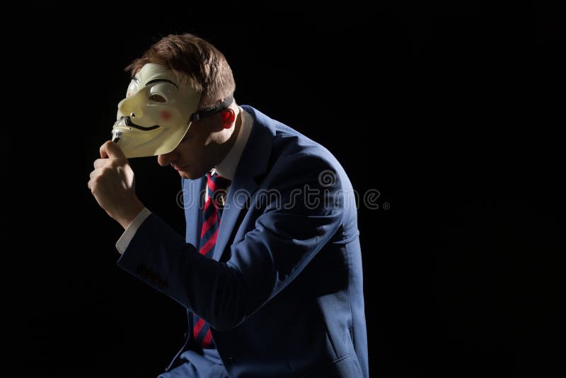 Business man under the mask disguise being Anonymous and implying that he is a hacker or anarchist. Business man under the mask disguise being Anonymous and implying that he is a hacker or anarchist.