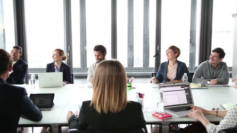 Bedrijfsmensen die bij lijst in conferentieruimte en het luisteren presentatie zitten